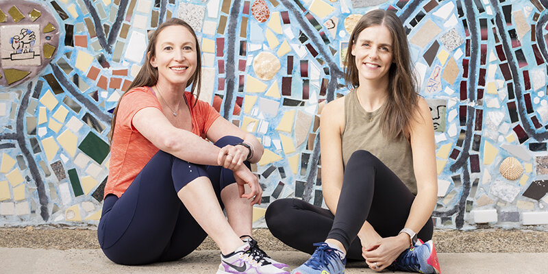 Co-owners Emily Leaman and Holly Waters sitting in front of a mosaic wall