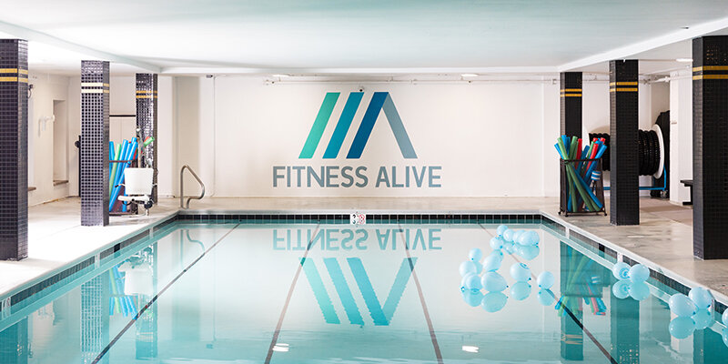 The Fitness Alive Center City pool with balloons and the logo on the wall