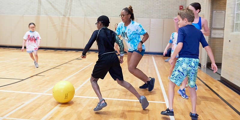 Campers chasing a yellow ball in the gym