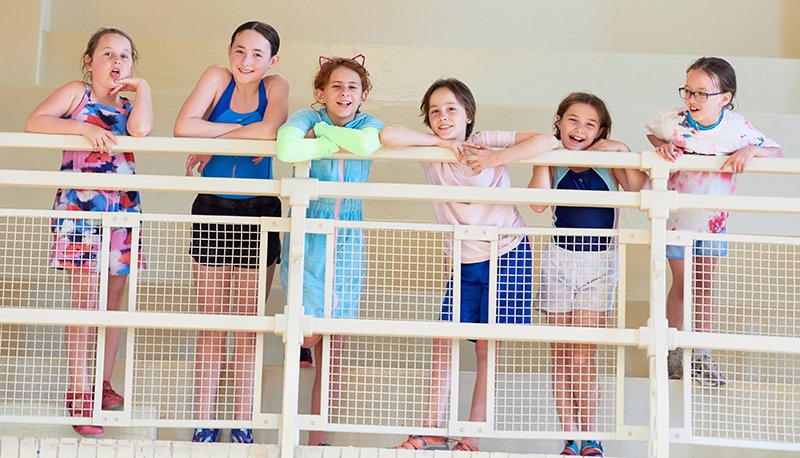 Campers smiling along the railing overlooking the pool