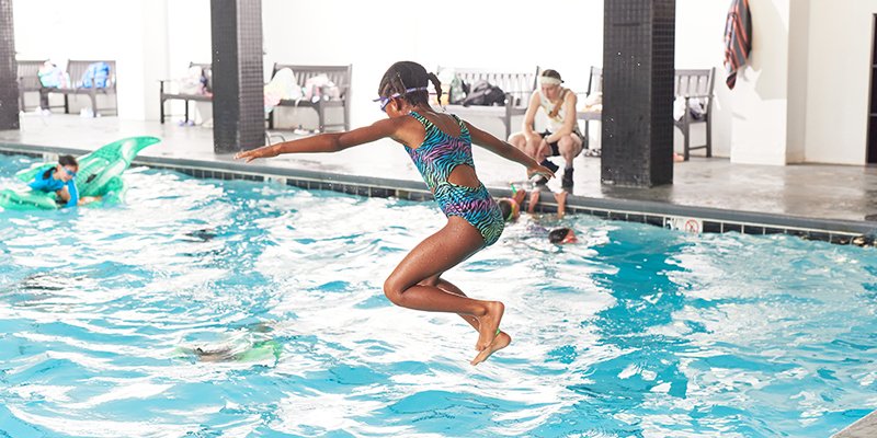 A camper leaps into the pool
