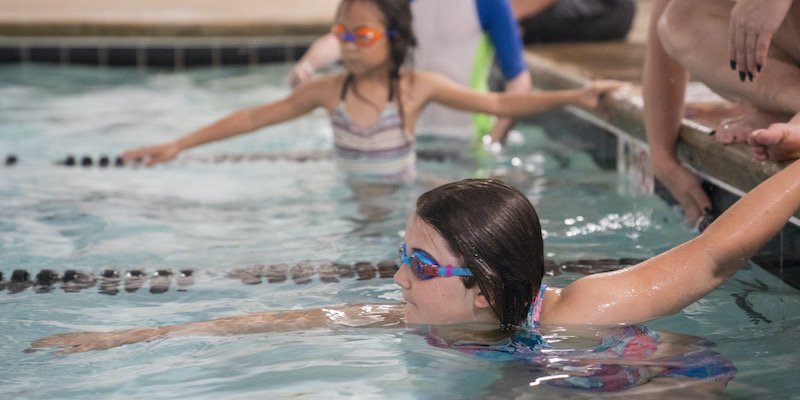 A girl practices her freestyle arm stroke along the lane line