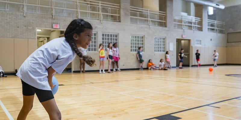 A camper gets ready to throw a ball in the gym