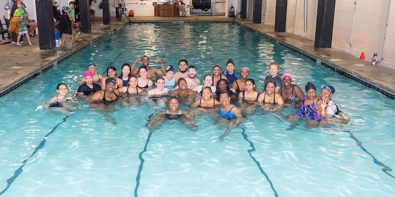 A big group of swimmers gathered in the pool at a community swim event