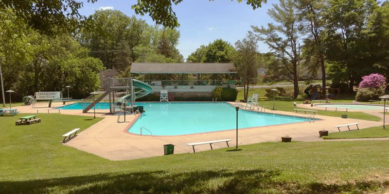 An outdoor pool surrounded by trees and lawn